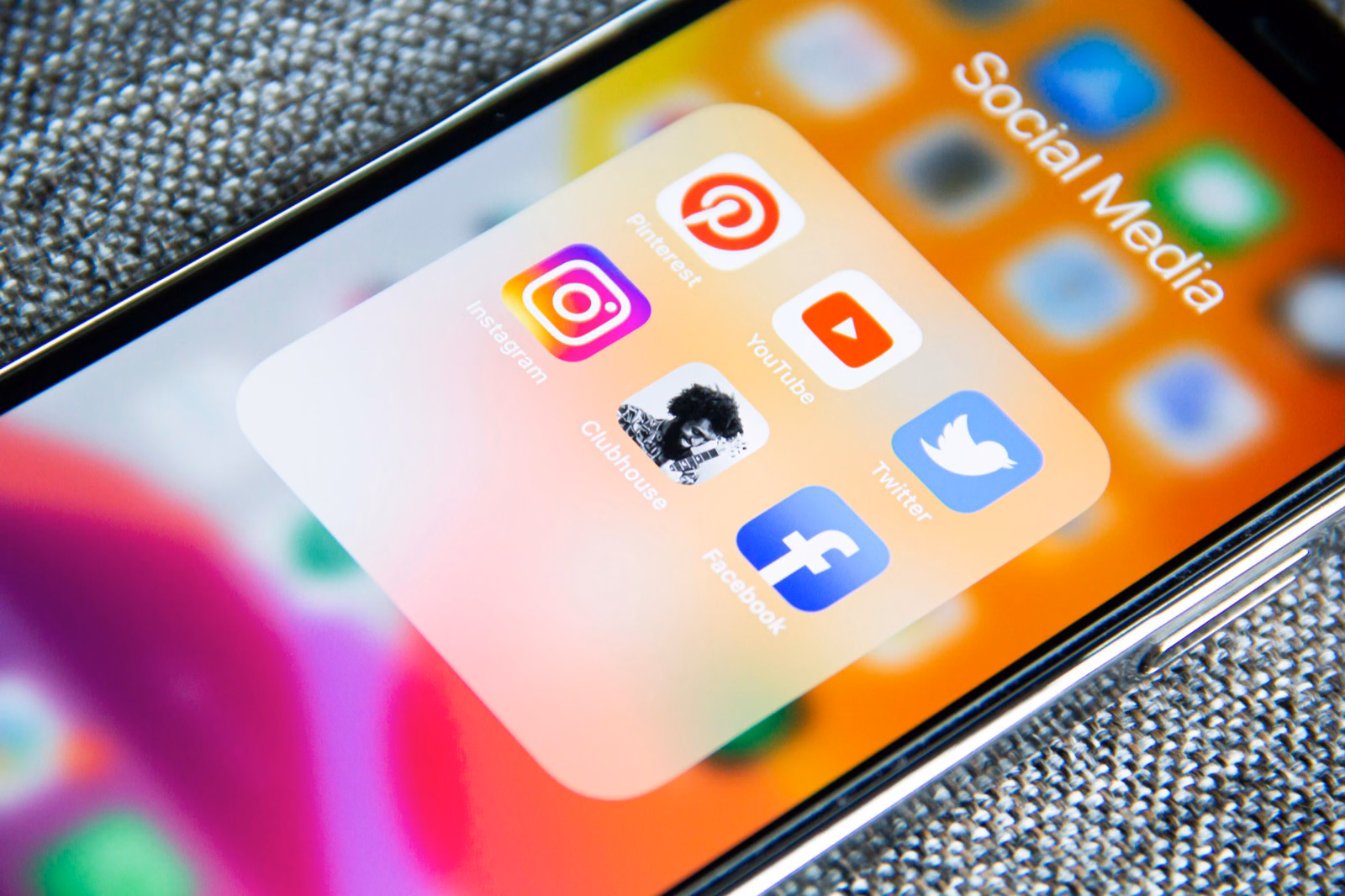 Close-up of an iPhone home screen showing the Social Media app folder with Instagram, YouTube, Twitter, and Facebook icons.