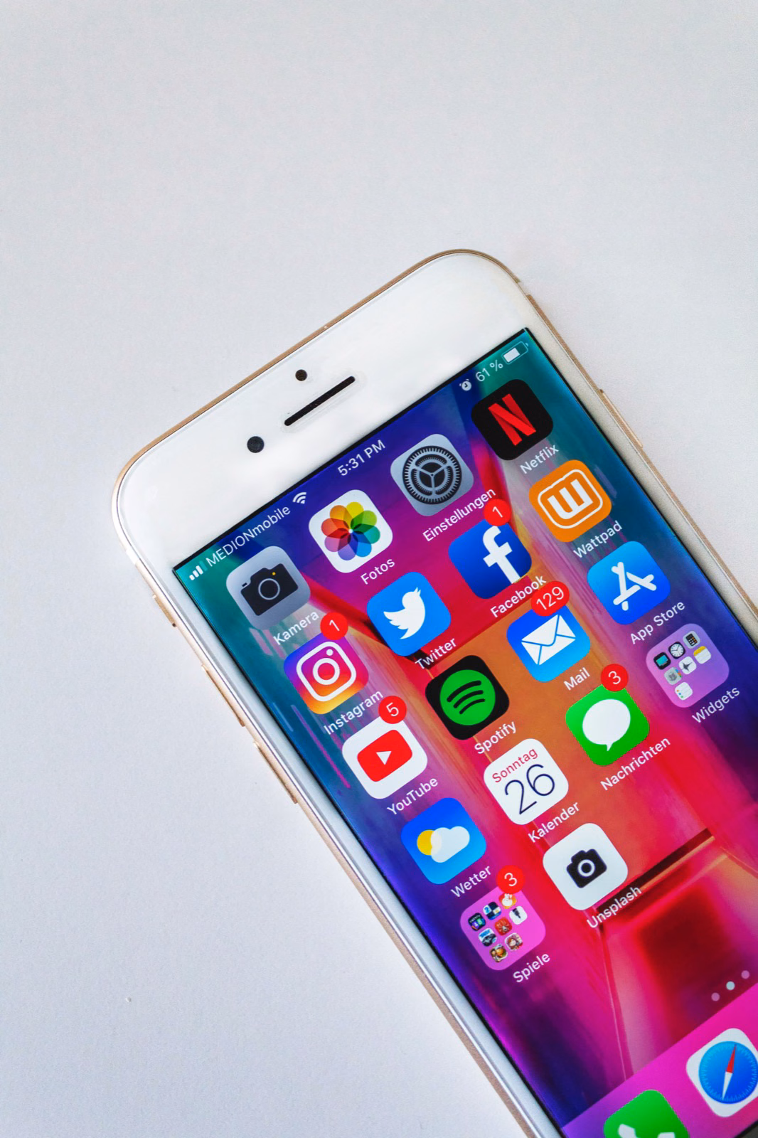 iPhone home screen showing a full grid of popular apps including financial and consumer applications on a colorful gradient background.