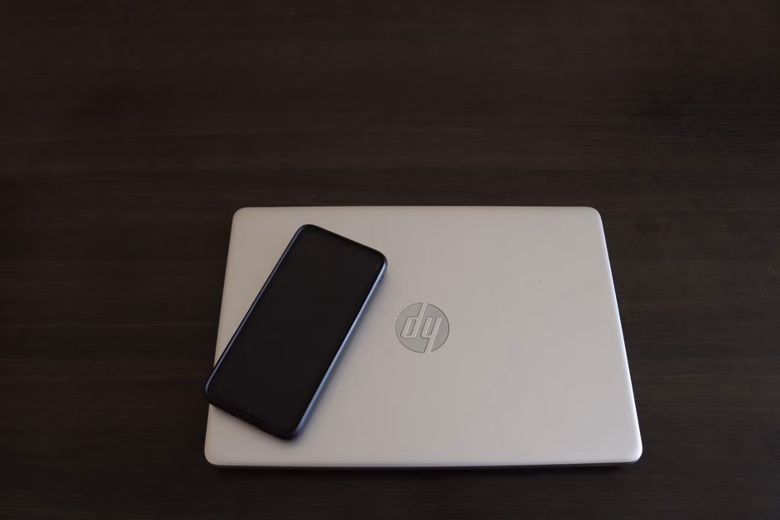 A laptop and smartphone side by side on an office desk, representing a B2B SaaS product paired with a mobile companion app