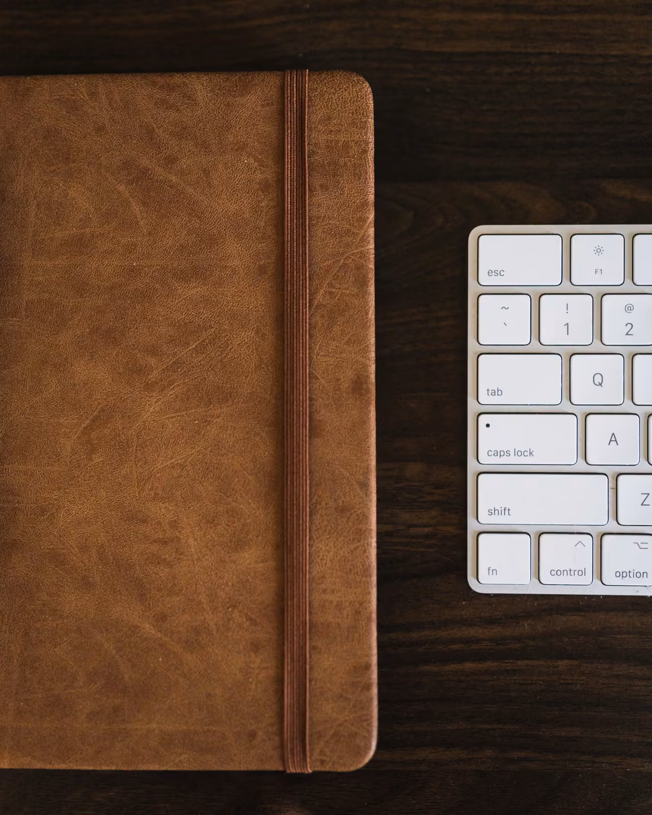 A leather notebook beside a Mac keyboard — the disciplined planning behind sprint zero.
