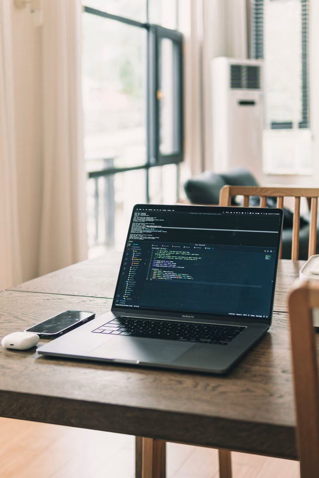 A laptop running code on a wooden desk — the engineering work behind a hard product.