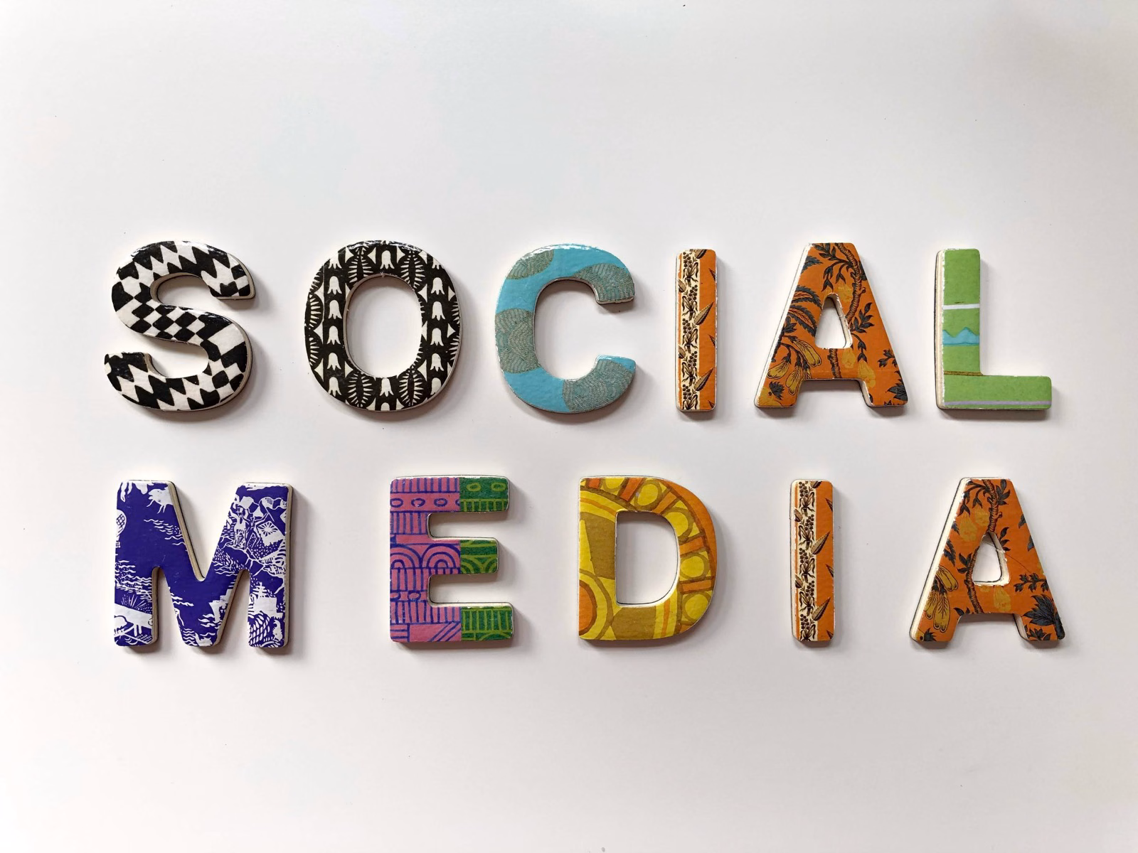 Decorative patterned wooden letters spelling Social Media arranged on a white background.